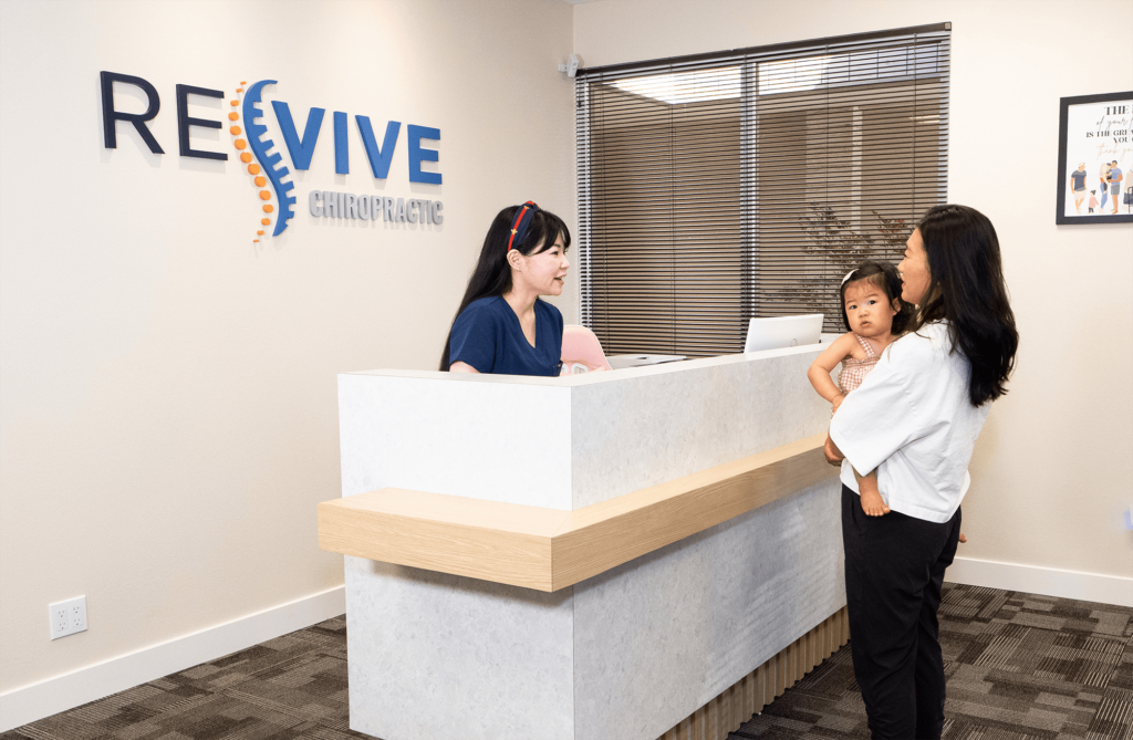 Chiropractor assistant welcoming patient with child at clinic reception