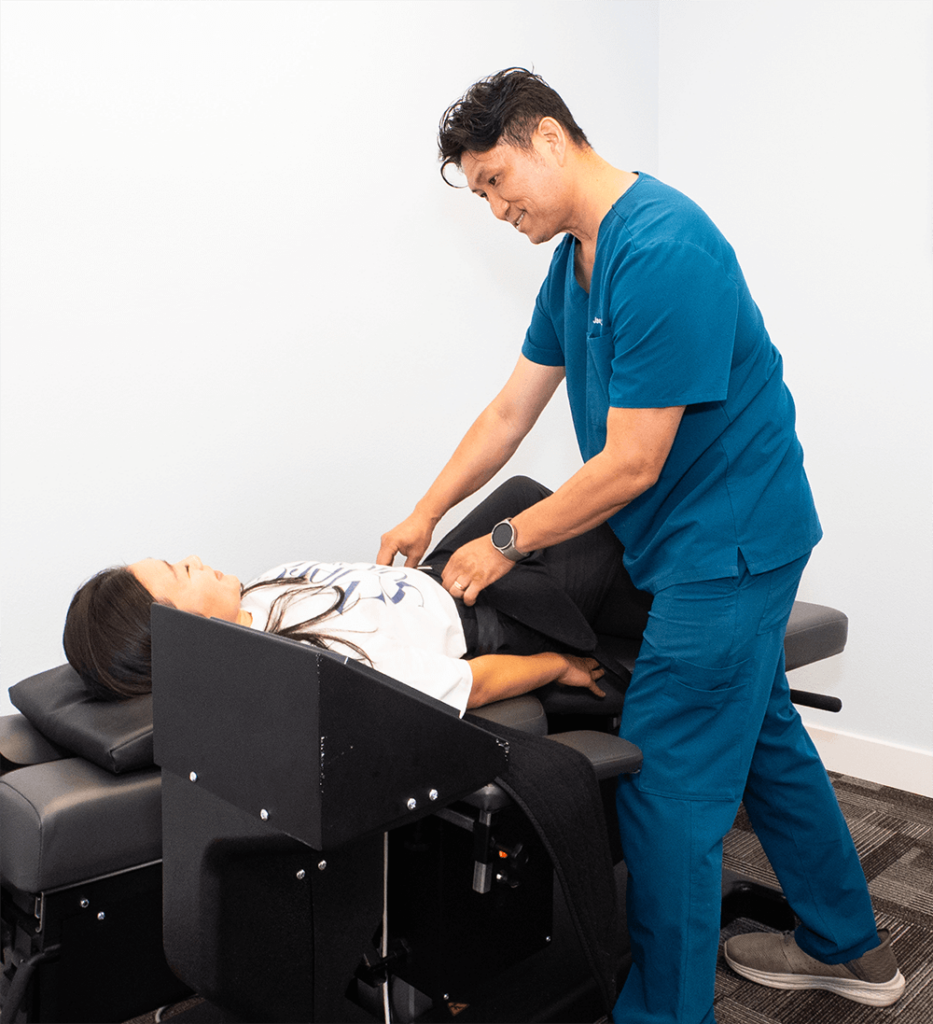 Jae ho Roh, D.C., chiropractor adjusting patient on treatment table